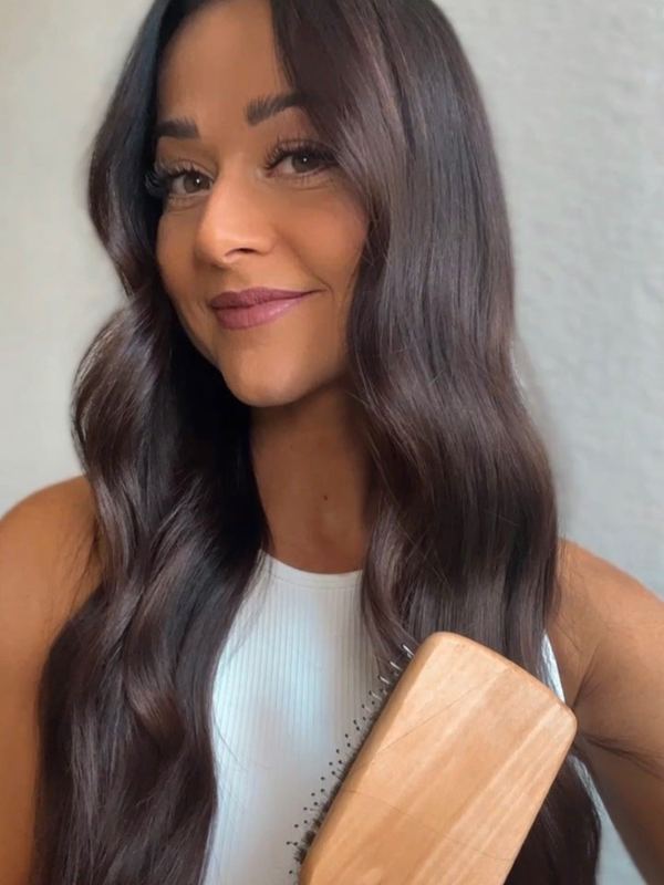 A customer brushing her hair with a 5 Birds brush
