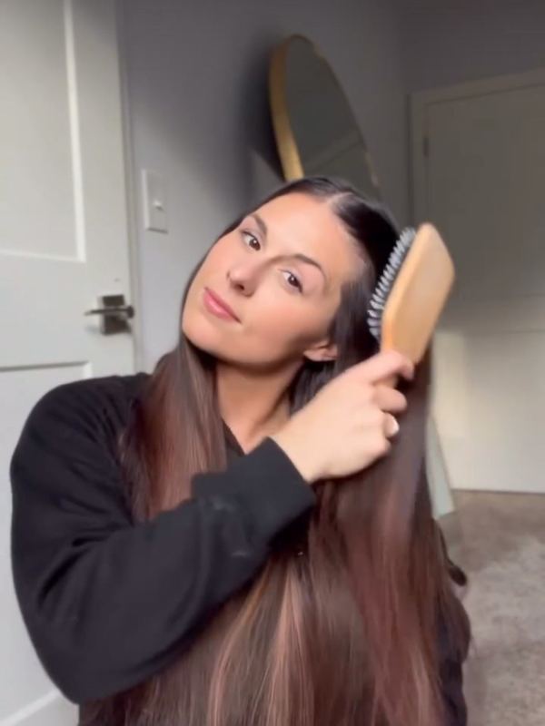 A customer brushing her hair with a 5 Birds brush