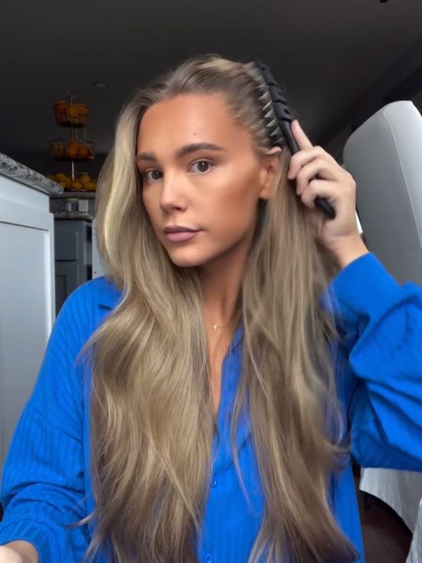 A customer brushing her hair with a 5 Birds brush