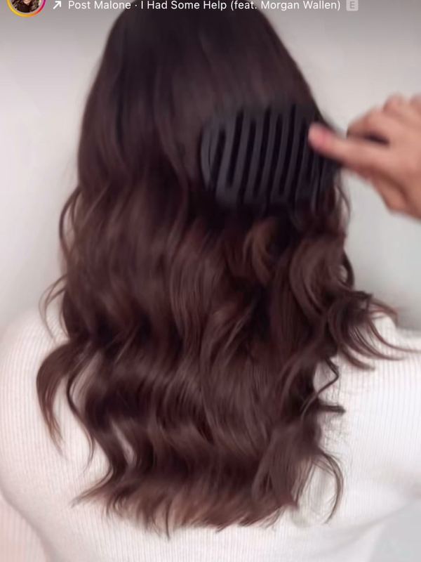 A customer brushing her hair with a 5 Birds brush