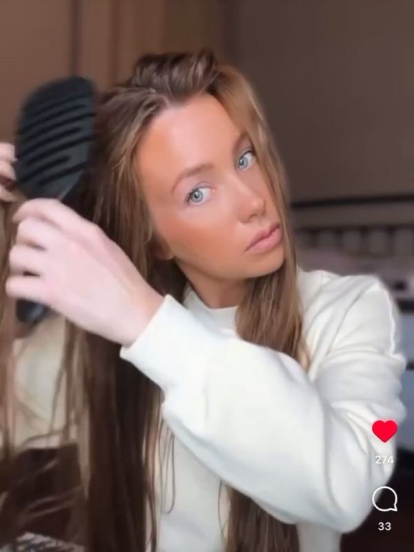 A customer brushing her hair with a 5 Birds brush