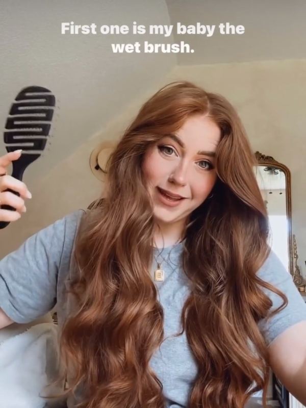 A customer brushing her hair with a 5 Birds brush