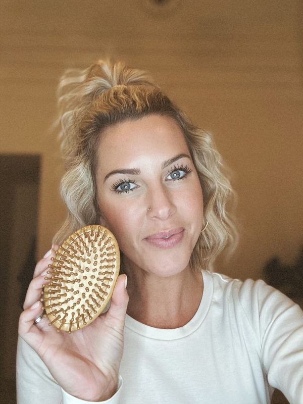 A customer brushing her hair with a 5 Birds brush