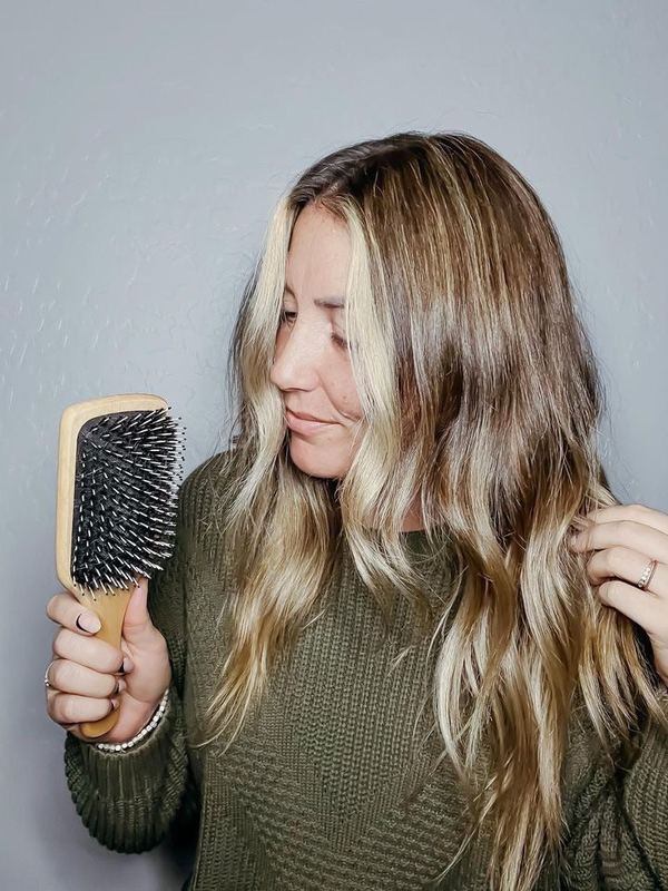 A customer brushing her hair with a 5 Birds brush